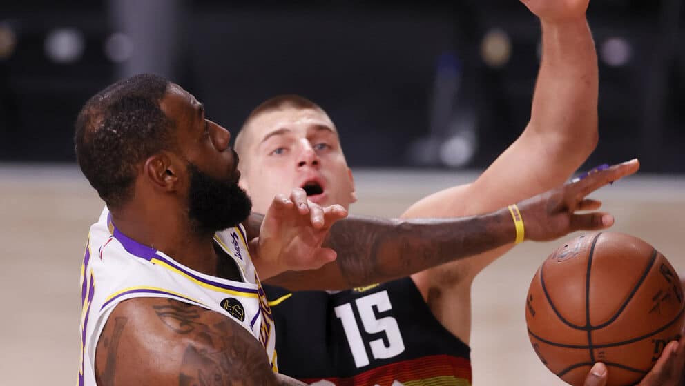 LeBron James (L) shoots past defending Denver Nuggets center Nikola Jokic