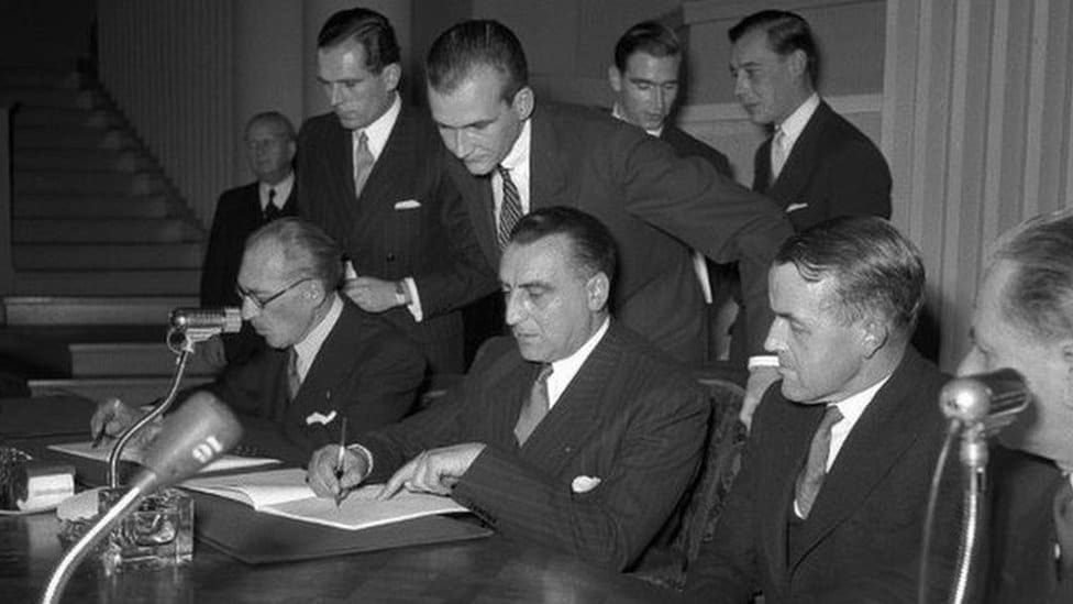 Ukrajina i Rusija: Šta je ratni zločin 2 Black and white photo of a group of men gathered around a table signing a document