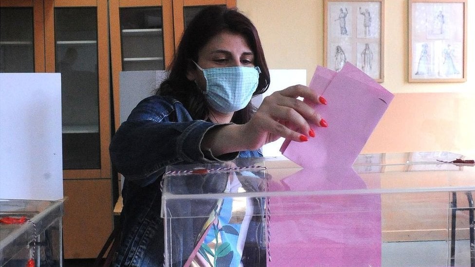 Žena ubacuje glasački listić u kutiju na parlamentarnim izborima 2020. godine