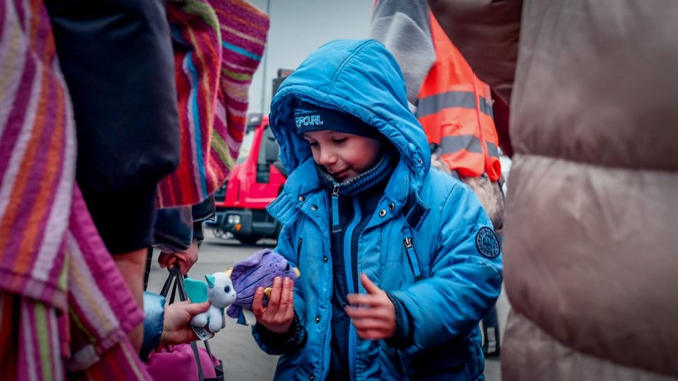 Two refugee children look at toys that they've been given