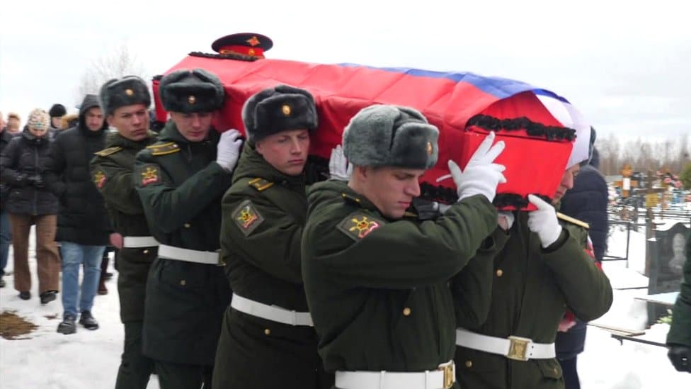 Rat u Ukrajini: Rusi tuguju za palim vojnicima 4 Russian servicemen carry a coffin draped in the national flag through a snowy cemetery