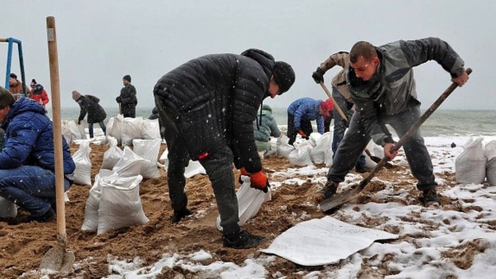 Ukrajina i Rusija: Da li će ključna luka Odesa biti sledeća ruska meta 6 People filling up bags of sand on a beach.