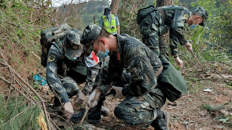 Avioni, Kina i nesreća: Srušio se avion sa više od 130 putnika - male šanse da je neko preživeo 3 Soldiers in camouflage fatigues searching the forested hillside of the crash site