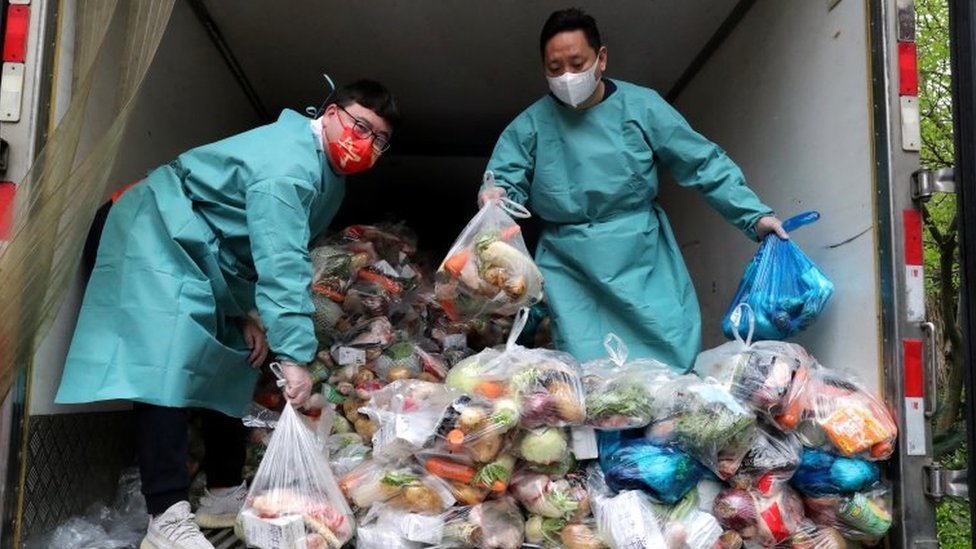 Korona virus i Kina: Muke zaključanih zbog kovida u Šangaju: Sve je manje hrane 1 Workers wearing protective gear sort bags of vegetables and groceries on a truck to distribute them to residents at a residential compound during lockdown in Shanghai on 5 April