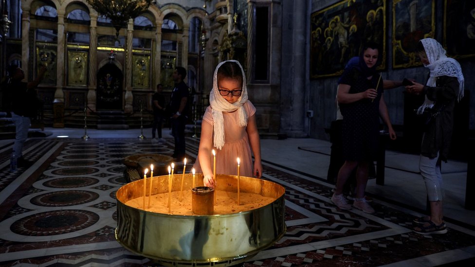 A girl places a candle in the Church of the Holy Sepulchre in Jerusalem's Old City (11 April 2022)