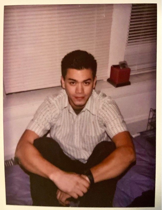 Tom Justice sitting cross-legged on the floor in front of windows