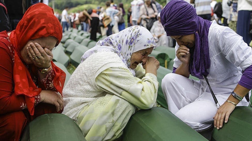 Bosnian Muslim women cry over the coffins of those murdered at Srebrenica