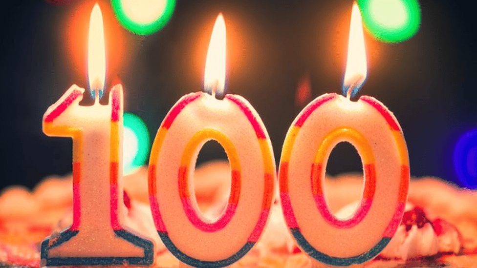 Candles for a 100th birthday, with flames melting the digits