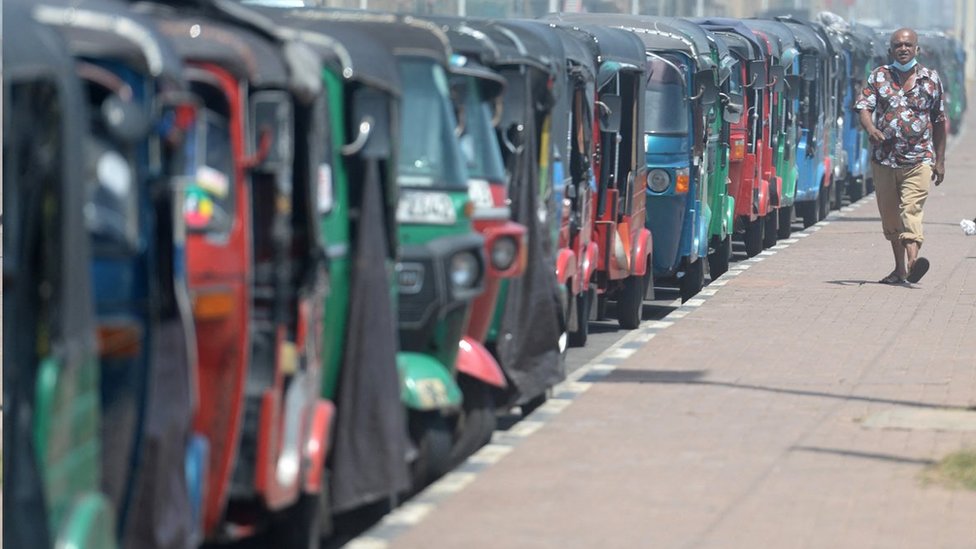 A man walks past autorickshaws waiting in a long queue for filling fuel at a petrol station in Colombo on July 14, 2022.