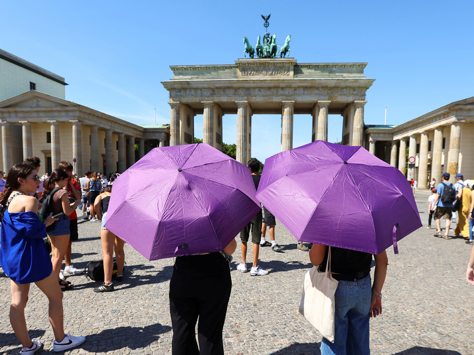 Toplotni talas u Nemačkoj - turisti u šetnji po gradu sa kišobranima