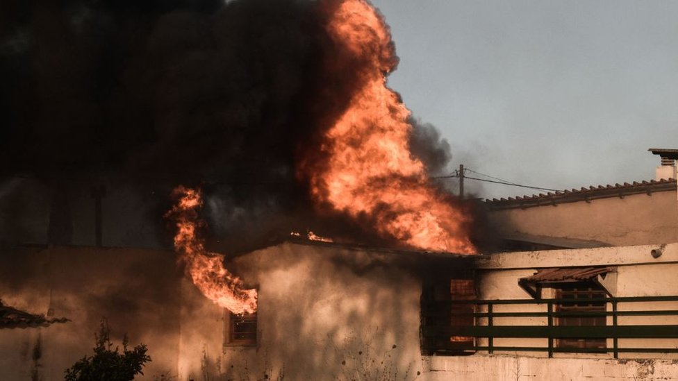 A house burns at the foot of Mount Penteli, near Athens, Greece