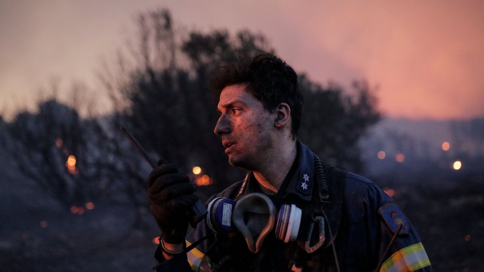 A firefighters speaking into his radio while battling a wildfire in Penteli, Greece on 19 July