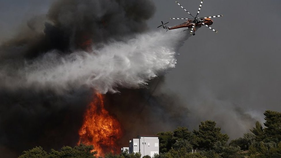 A firefighting helicopter tries to extinguish a wildfire threatening houses at the north-east suburb of Pallini, near Athens, Greece, 20 July 2022.
