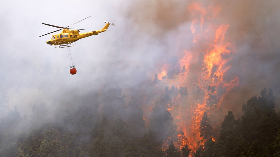 A helicopter drops water on a fire.