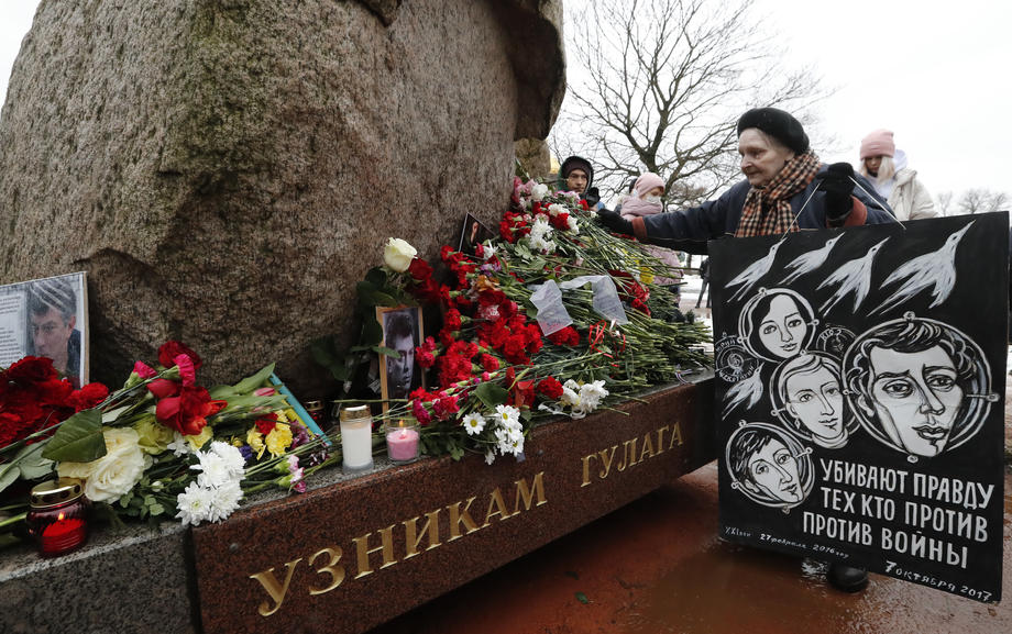 epa09040068 A woman lays flowers at the monument to all political prisoners during an event marking the sixth anniversary of Boris Nemtsov assassination, in St. |Petersburg, Russia, 27 February 2021. Boris Nemtsov was killed on 27 February 2015 by suspected Chechen hitmen on a bridge in front of the Kremlin. The poster reads: ?Killing the Truth?. 