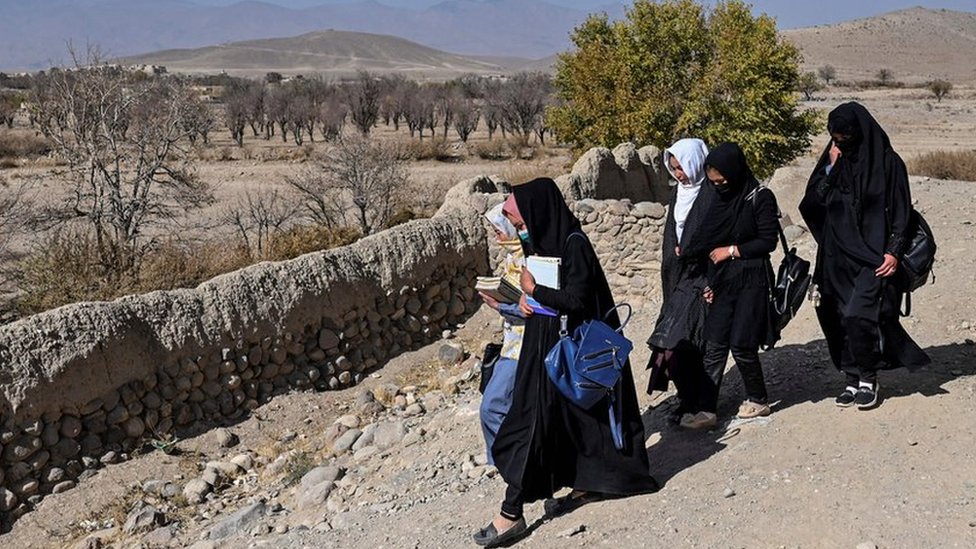 Afghan female students walk to university holding books