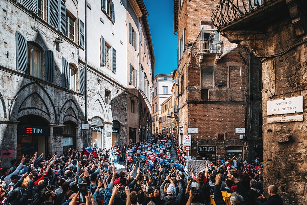 Gledaoci u uskoj ulici u italijanskoj Sijeni gledaju bicikliste dok voze 12. etapu takmičenja Điro d' Italija 2021. godine