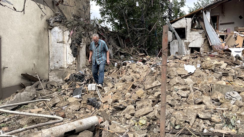 A man, followed by a dog, walks among the rubble of a destroyed property in Mykolaiv, Ukraine