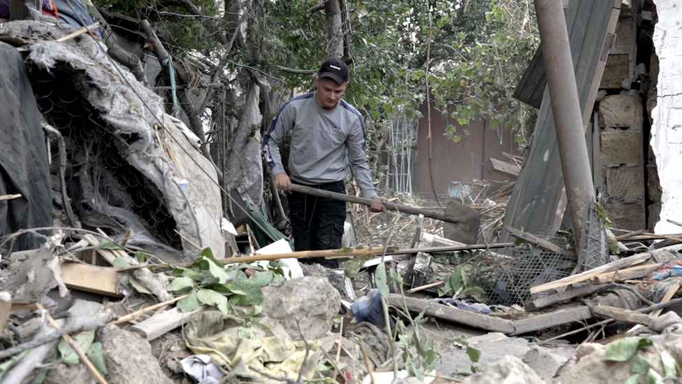A young man attempts to clear debris caused by Russian strikes on Mykolaiv