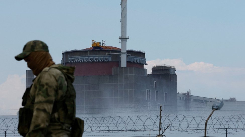 A serviceman with a Russian flag on his uniform stands guard near the Zaporizhzhia Nuclear Power Plant