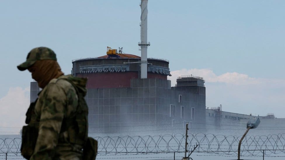 Rusija i Ukrajina: Eksplozije u ruskoj vojnoj bazi na Krimu, Amerika šalje novih milijardu dolara vojne pomoći Ukrajini 8 A serviceman with a Russian flag on his uniform stands guard near the Zaporizhzhia Nuclear Power Plant