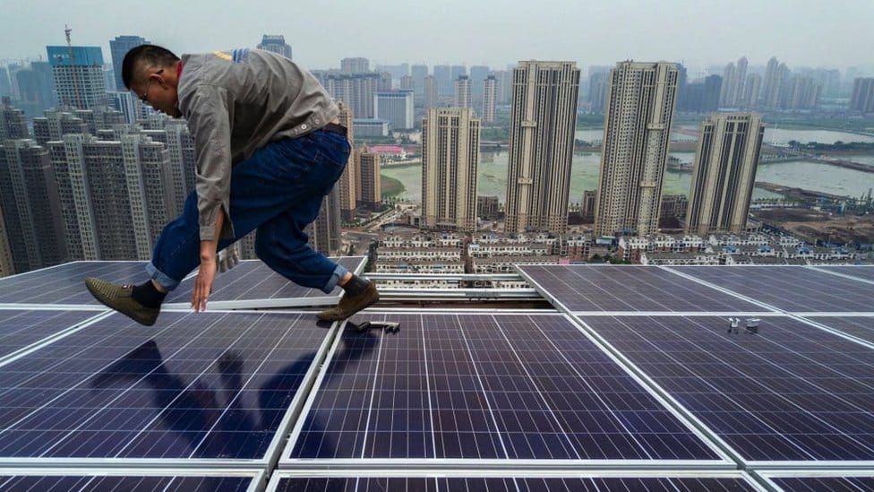 A Chinese worker from Wuhan Guangsheng Photovoltaic Company works on a solar panel project on the roof of a 47 story building in a new development on May 15, 2017 in Wuhan, China
