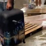 Na aerodromu prokišnjava, putnici vuku kofere preko drvenih paleta da bi prešli bare kišnice 10