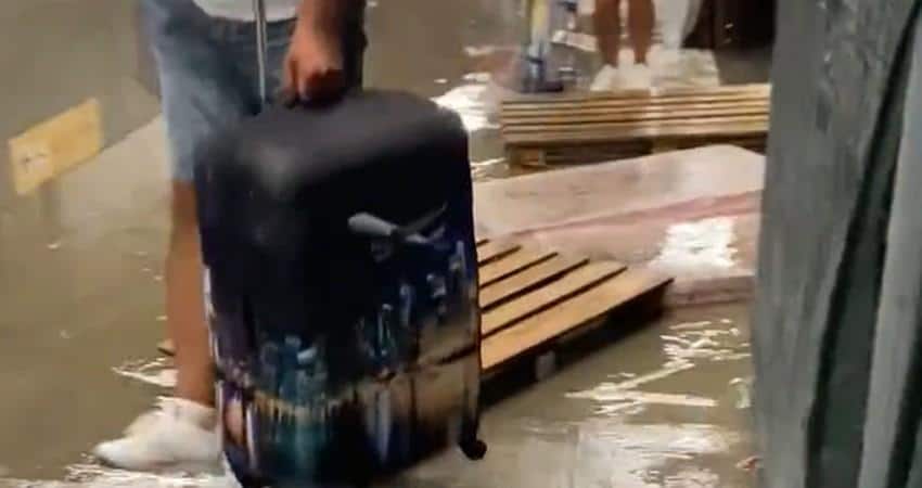 Na aerodromu prokišnjava, putnici vuku kofere preko drvenih paleta da bi prešli bare kišnice 1