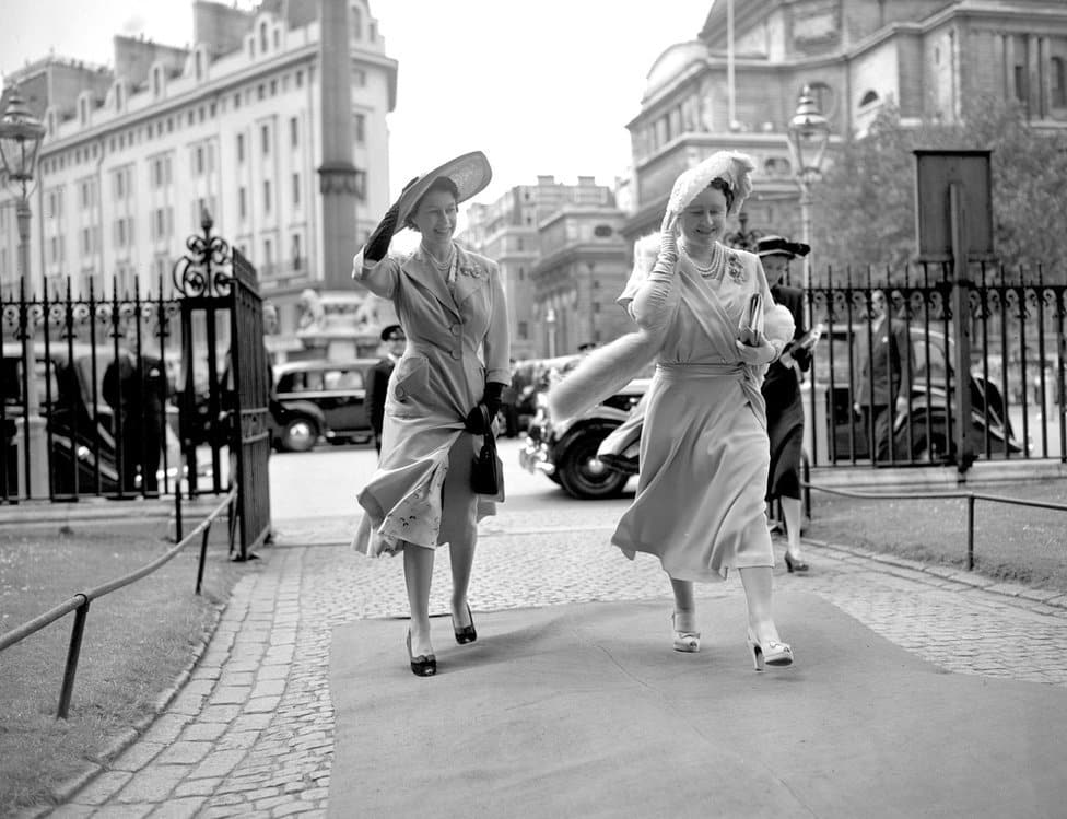 Kraljica Elizabeta Druga: Život u fotografijama 9 Queen Elizabeth and Princess Elizabeth hold on to their hats as they arrive at Westminster Abbey to attend the wedding of Lady Caroline Montagu-Douglas-Scott to Mr Ian Hedworth Gilmour