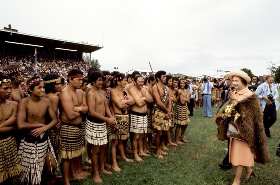Kraljica Elizabeta Druga: Život u fotografijama 25 Queen Elizabeth II, wearing a cloak of brown kiwi feathers, with Maori warriors at Rugby Park, Gisborne, when she and the Duke of Edinburgh received a New Zealand Maori welcome at the opening of the Royal New Zealand Polynesian Festival.