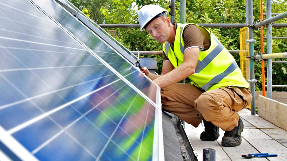 Srbija i energetika: Kako uštedeti struju i može li menjanje sijalica da ublaži energetsku krizu 6 Stock image of a workman fixing solar panels to a house