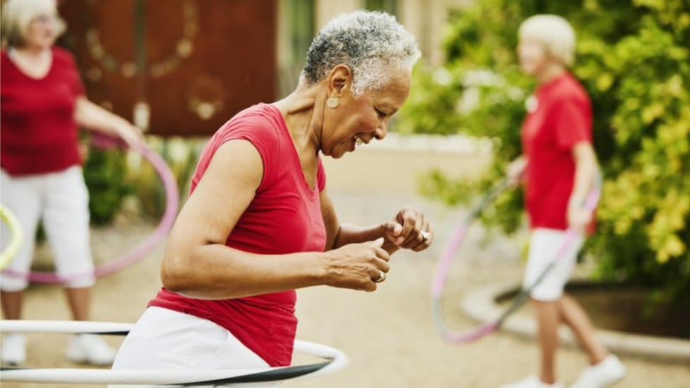 An elderly black woman exercising with a hoola hoop