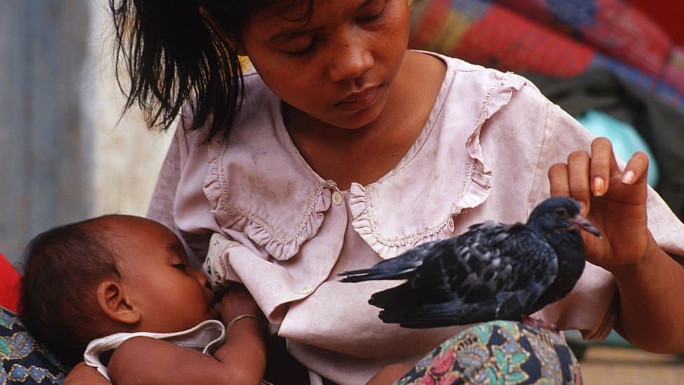 UN i Indeks humanog razvoja: Globalni pad životnog veka, obrazovanja i zarada, Balkan prati trend 1 A young Cambodian mother feeding her baby and petting a pigeon