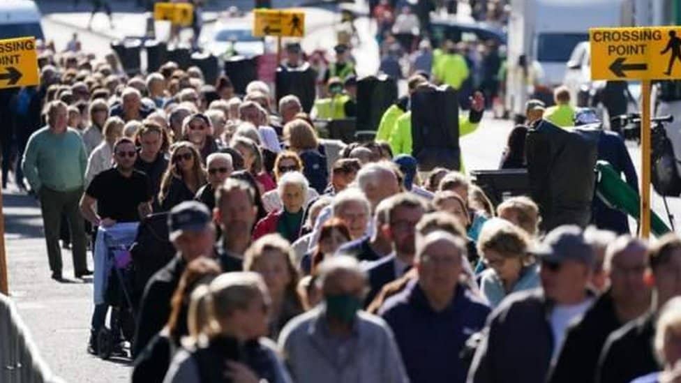 ljudi u povorci čekaju da odaju poštu kraljici