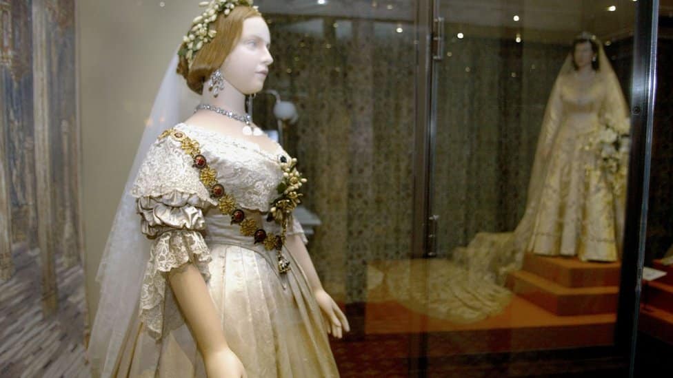 A mannequin of Britain's Queen Victoria, wearing her wedding dress, standing in front of a mannequin of Queen Elizabeth II also wearing her wedding dress