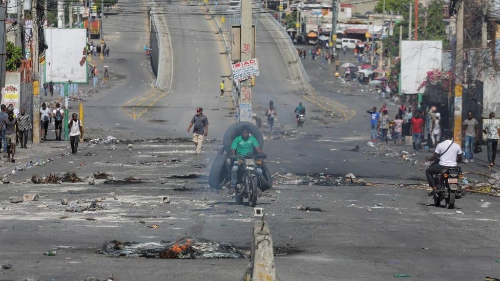 Ljudi u praznoj ulici sa ostacima barikada tokom nacionalnog štrajka protiv poskupljenja goriva, u Port-o-Prensu, Haiti, 26. septembra 2022.