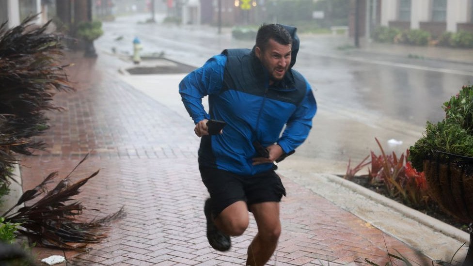 Brent Shaynore runs to a sheltered spot through the wind and rain from Hurricane Ian in Sarasota, Florida