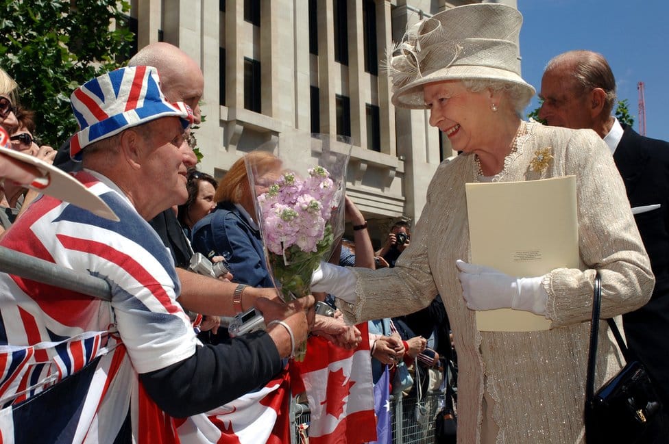 Queen Elizabeth II accepts flowers from Royal fan Terry Hutt outside at St Paul's Cathedral, London, after a service of thanksgiving in honour of her 80th birthday