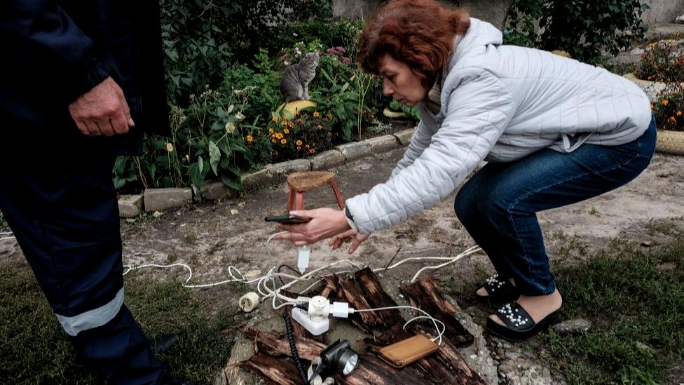 Rusija i Ukrajina: Apel Ukrajincima da štede struju, ruske vlasti ozbiljno razmatraju povlačenje trupa iz Hersona, smatraju britanski obaveštajci 2 Woman charging phone with generator in Kupiansk, Kharkiv region, 24 Sep 22