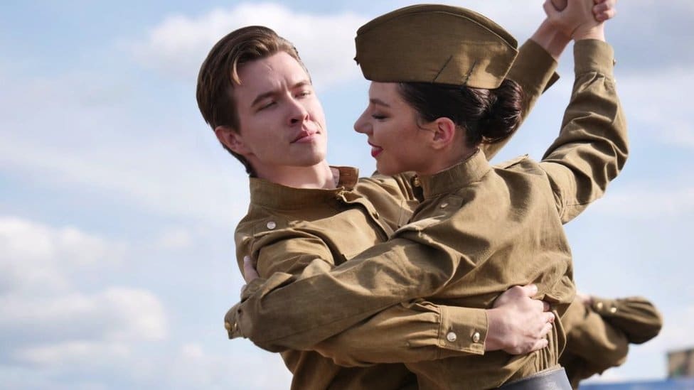 A man and a woman in Soviet military uniforms are dancing a waltz