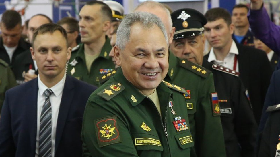 Russian defence minister Sergei Shoigu, in military uniform, surrounded by his staff