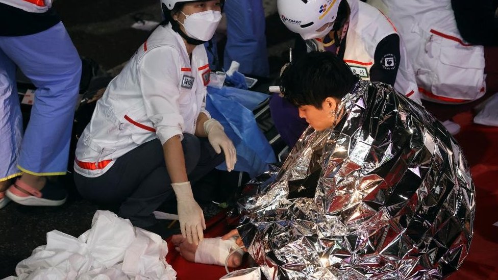A man receives medical help from rescue team members at the scene where dozens of people were injured in a stampede during a Halloween festival in Seoul, South Korea, October 29, 2022
