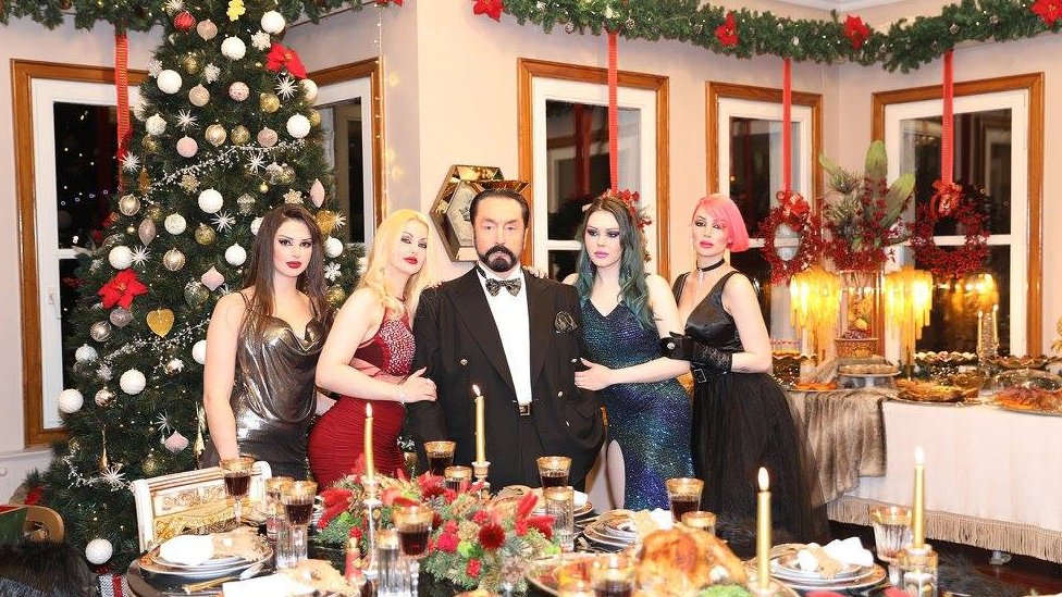 Turska i seksualno nasilje: Tele-propovednik u Turskoj osuđen na 8.658 godina zatvora 2 Adnan Oktar stands in a room decorated for Christmas, surrounded by four women on his arms with varying dyed hair colours