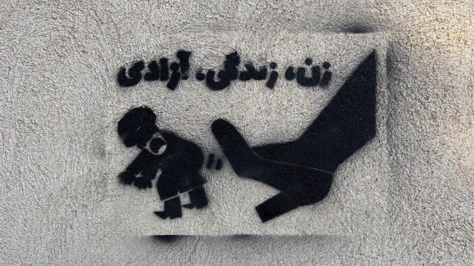 Grafiti su još jedno sredstvo kojim se koriste demonstranti u Iranu - ovde vidimo žensku cipelu kako udara policajca, ispod piše žene, život i sloboda