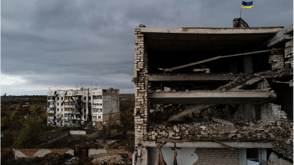 A Ukrainian flag flies over a ruined apartment block in he recaptured village of Archangelske, in Kherson province
