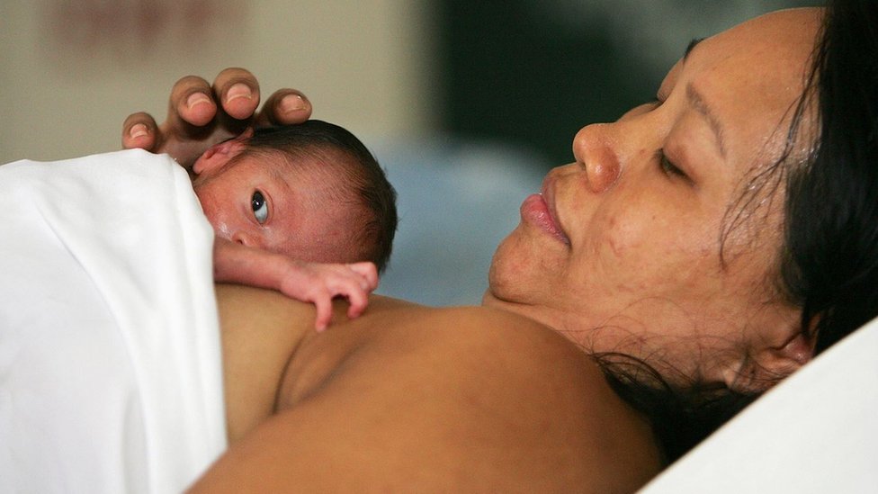 A mother holding her infant baby to her chest