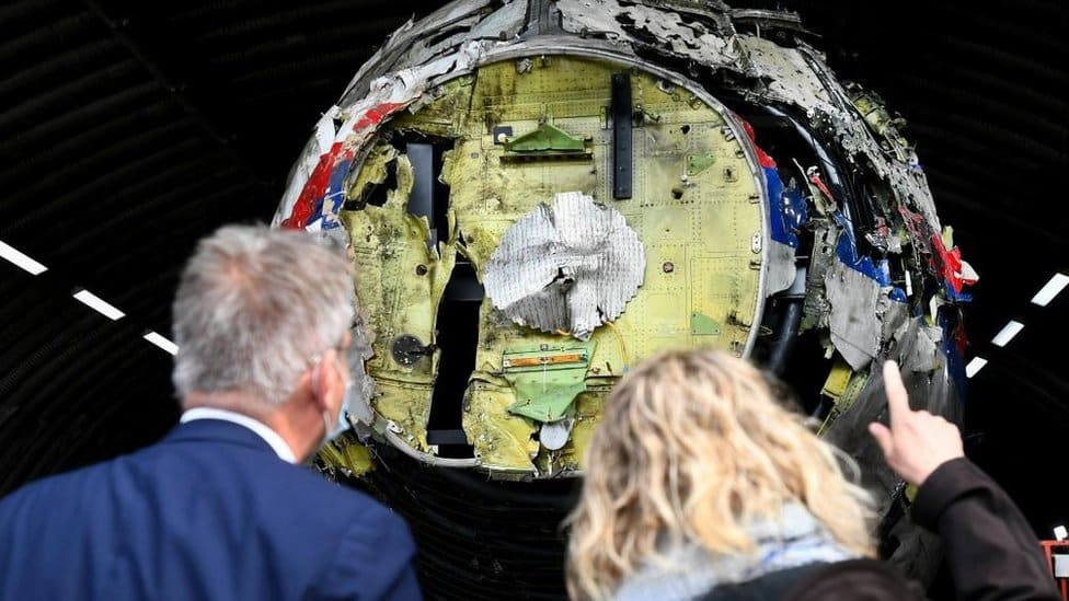 Two people inspect a reconstruction of the MH17 wreckage
