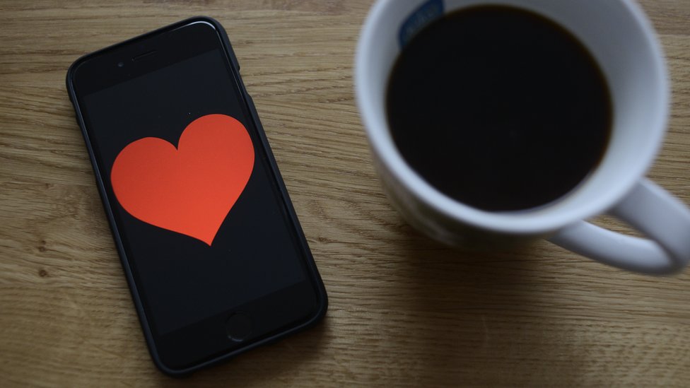 A coffee cup and a smartphone with a heart on the screen