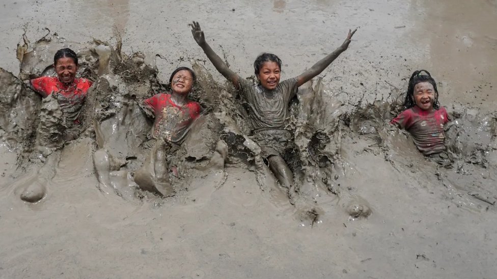Grupa dece uživa u kupanju u blatu tokom nepalskog Nacionalnog dana pirinčanog polja, kojim se obeležava početak sezone sadnje pirinča
