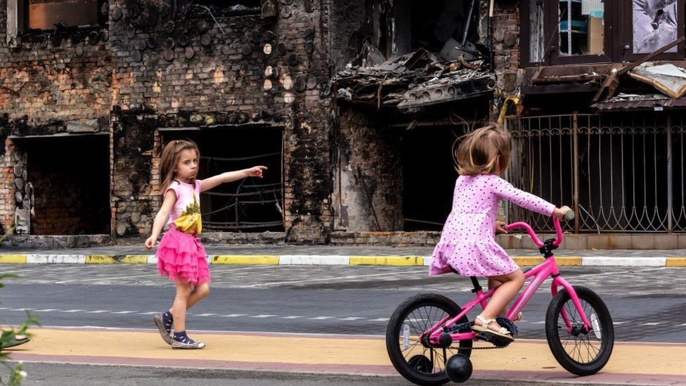 Two girls are seen in front a residential area affected by bombardment in the Ukrainian city of Bucha